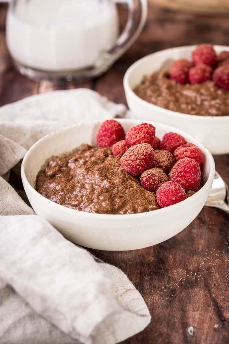 Chocolate Porridge in a bowl with fresh raspberries and dusting of cocoa powder.