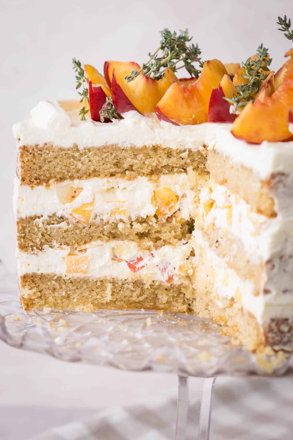 Nectarine Thyme Limoncello Cake cut into showing soft and fluffy sponge and light creamy filling stuffed with nectarines.
