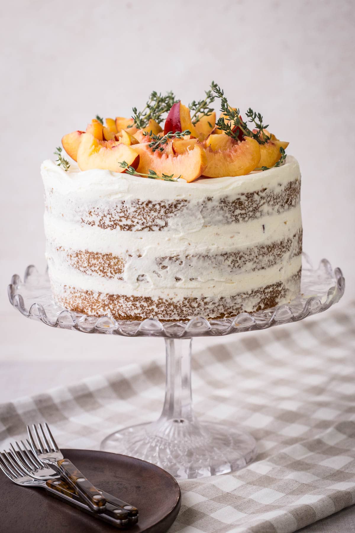 Nectarine Thyme Limoncello Cake with fresh cream covering decorated in the naked style and topped with fresh nectarines and thyme.