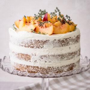 Nectarine Thyme Limoncello Cake with fresh cream covering decorated in the naked style and topped with fresh nectarines and thyme.