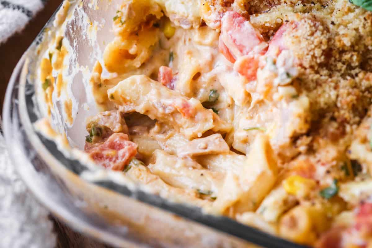 A dish of Gluten-Free Tuna Pasta Bake with a portion taken out showing creamy delicious inside.