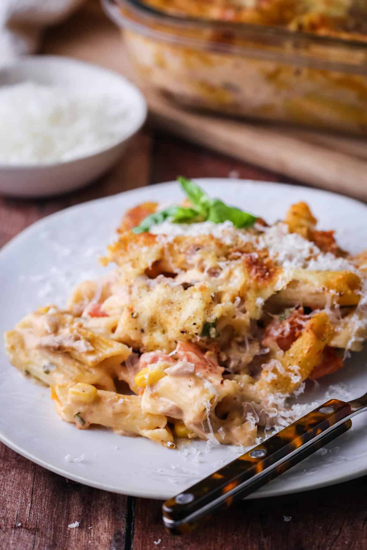 A portion of Gluten-Free Tuna Pasta Bake on a plate with extra cheese scattered on top.