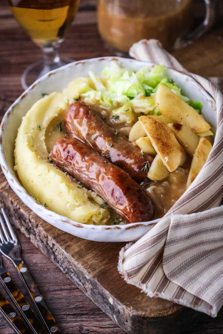Sausages, gravy, caramelised apples and cabbage in a bowl with lashings of rich onion gravy.