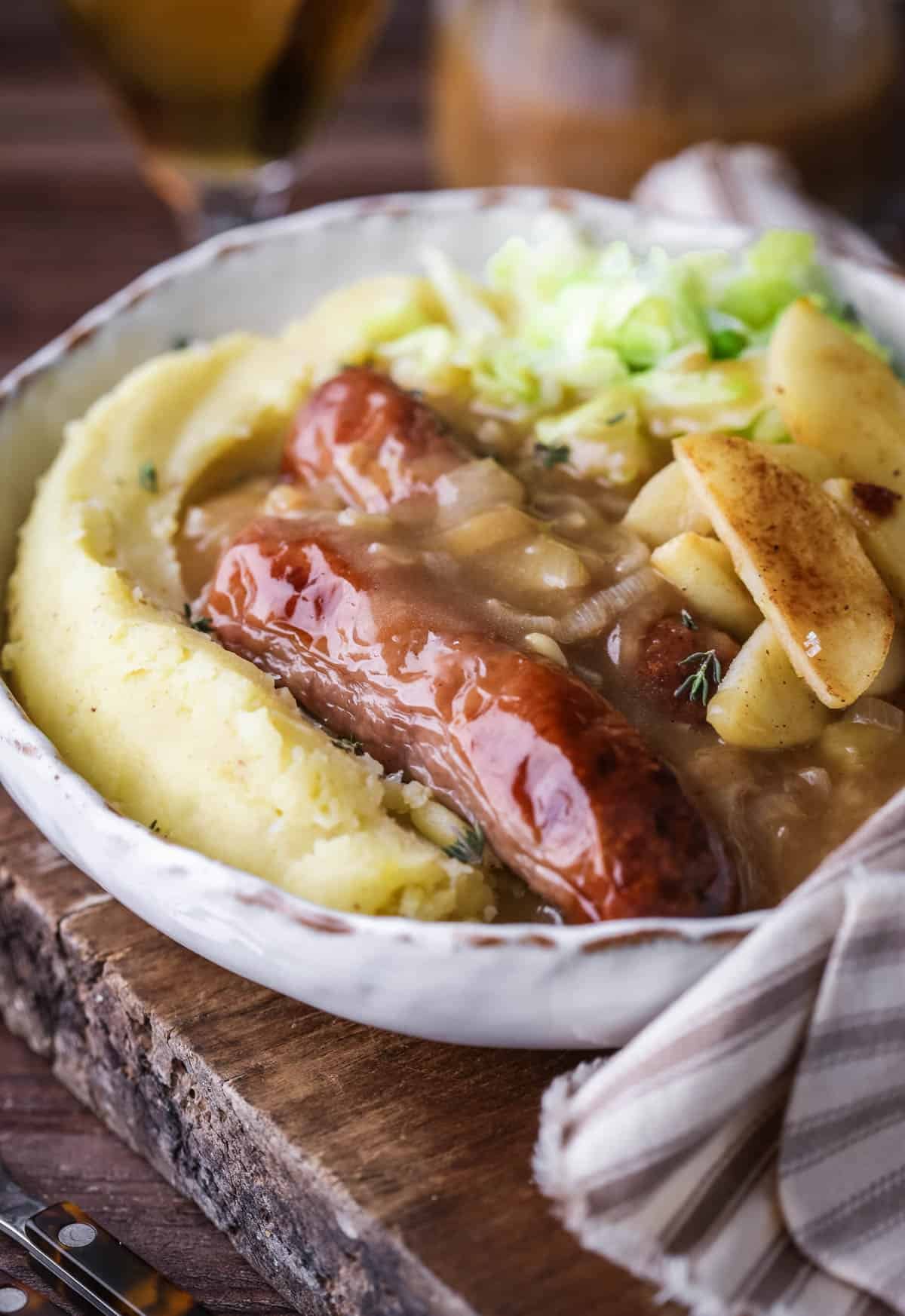 Sausages, gravy, caramelised apples and cabbage in a bowl with lashings of rich onion gravy.
