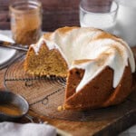 Sweet Potato Cake on wire rack covered in sweet maple cream cheese icing and dusted with cinnamon. Cut showing rich sponge inside with cinnamon swirl rippling through.