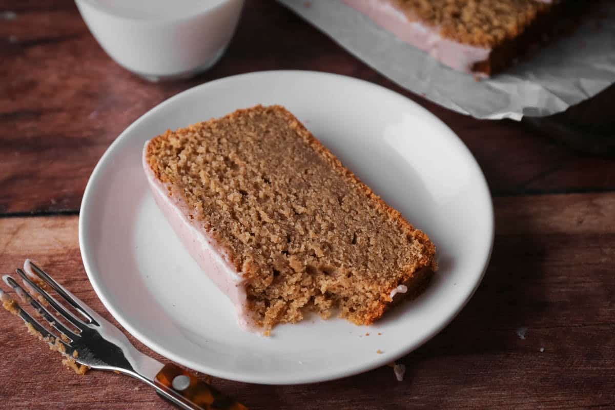 Slice of apple butter cake on a plate with forkful showing soft crumb.