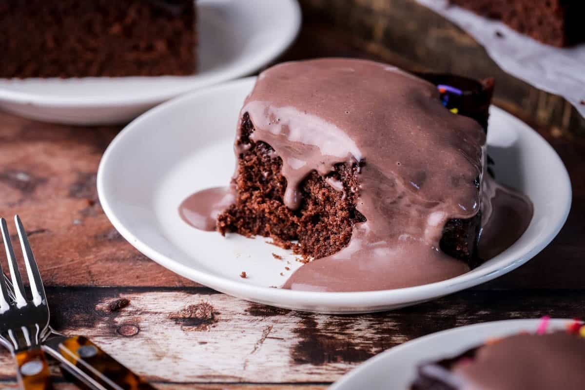 Smooth chocolate custard poured over a slice of chocolate cake showing it dripping down the tender crumb.