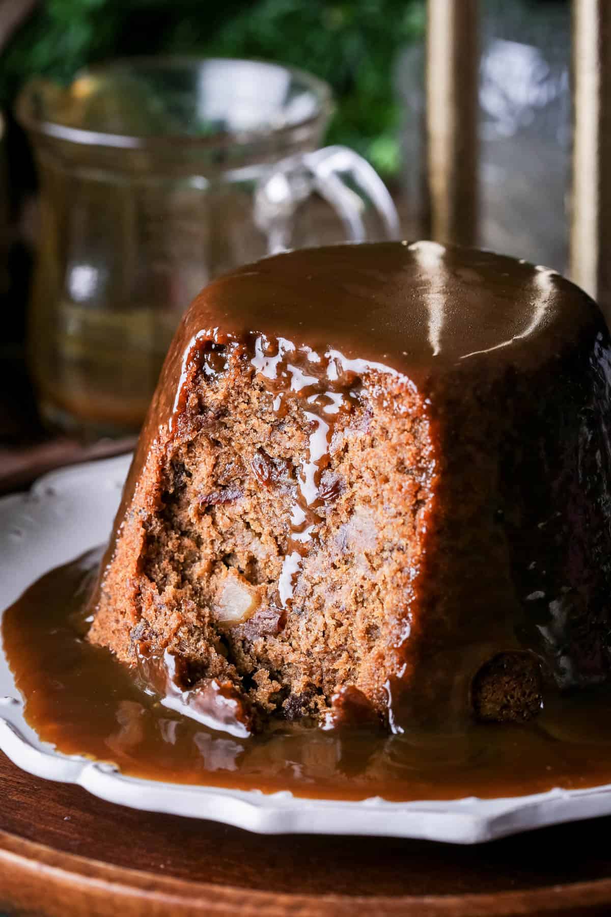 Sticky Toffee Pudding cut showing soft inside loaded with juicy fruit. Sticky Toffee Sauce drizzling down.