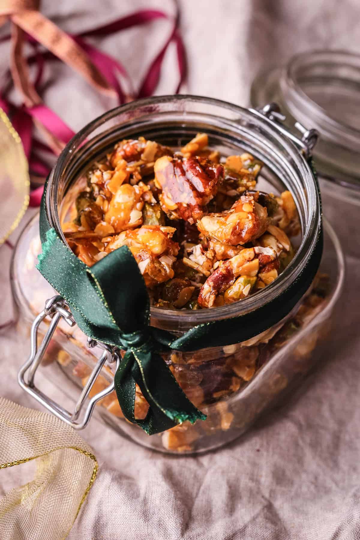 Caramelised Mixed Nuts in a glass jar wrapped with a festive ribbon.