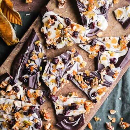 Christmas Chocolate Bark snapped into shards on a wooden board.