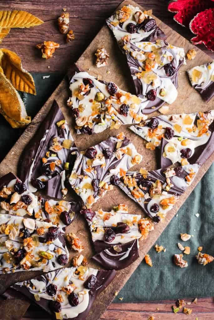 Christmas Chocolate Bark snapped into shards on a wooden board.