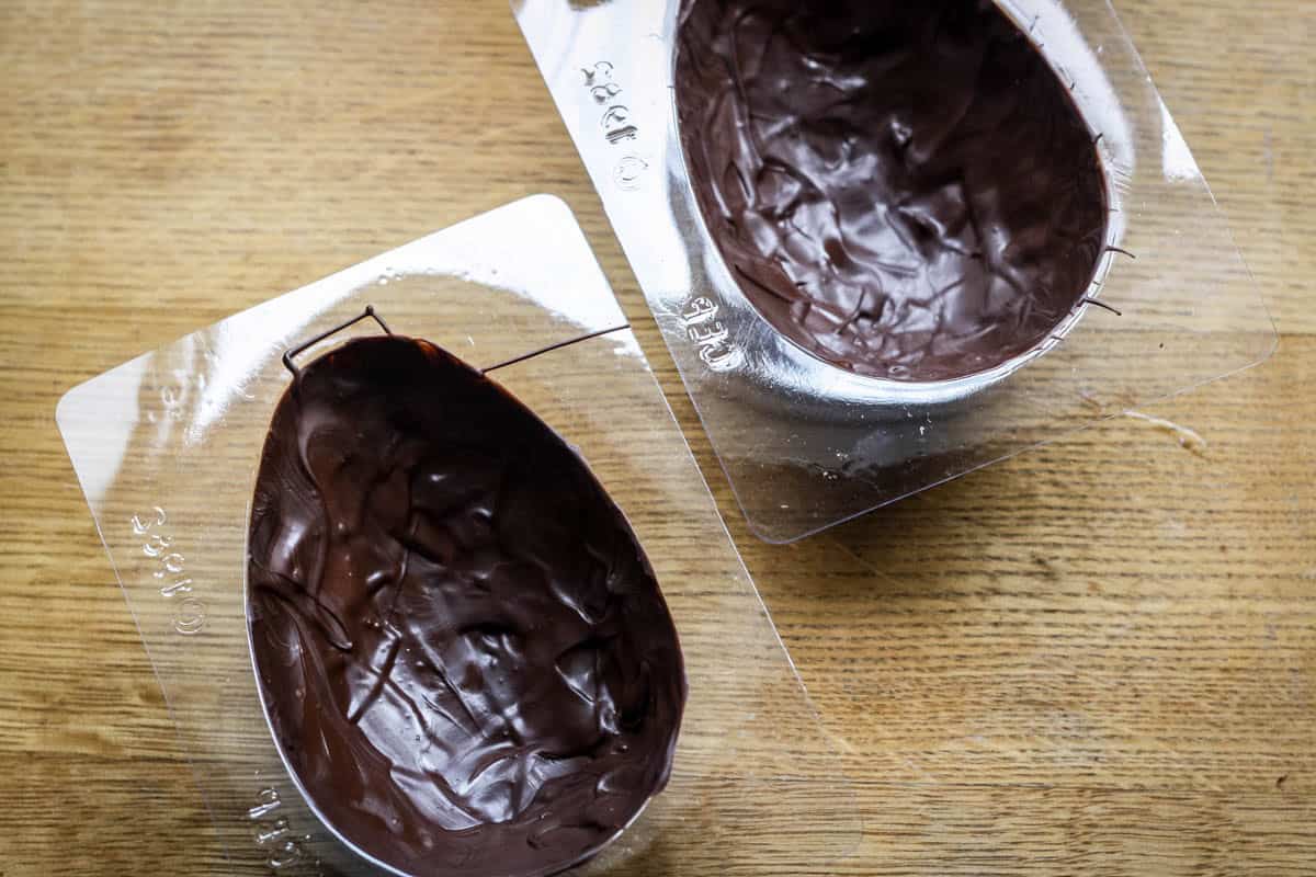 Tempered chocolate poured into easter egg mould.