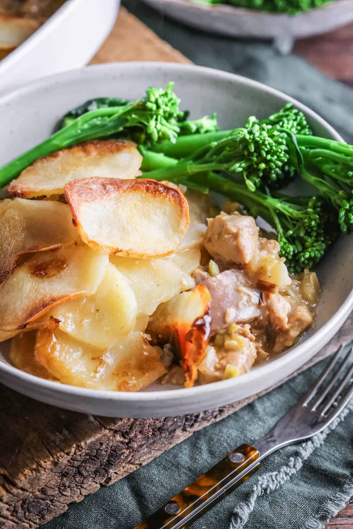 A bowl of Turkey Hotpot showing crisp potatoes and creamy turkey filling. Served with tenderstem broccoli.