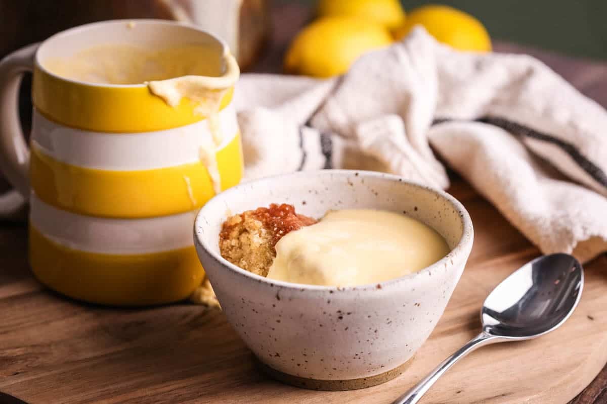 Lemon custard poured over lemon sponge pudding in a bowl.