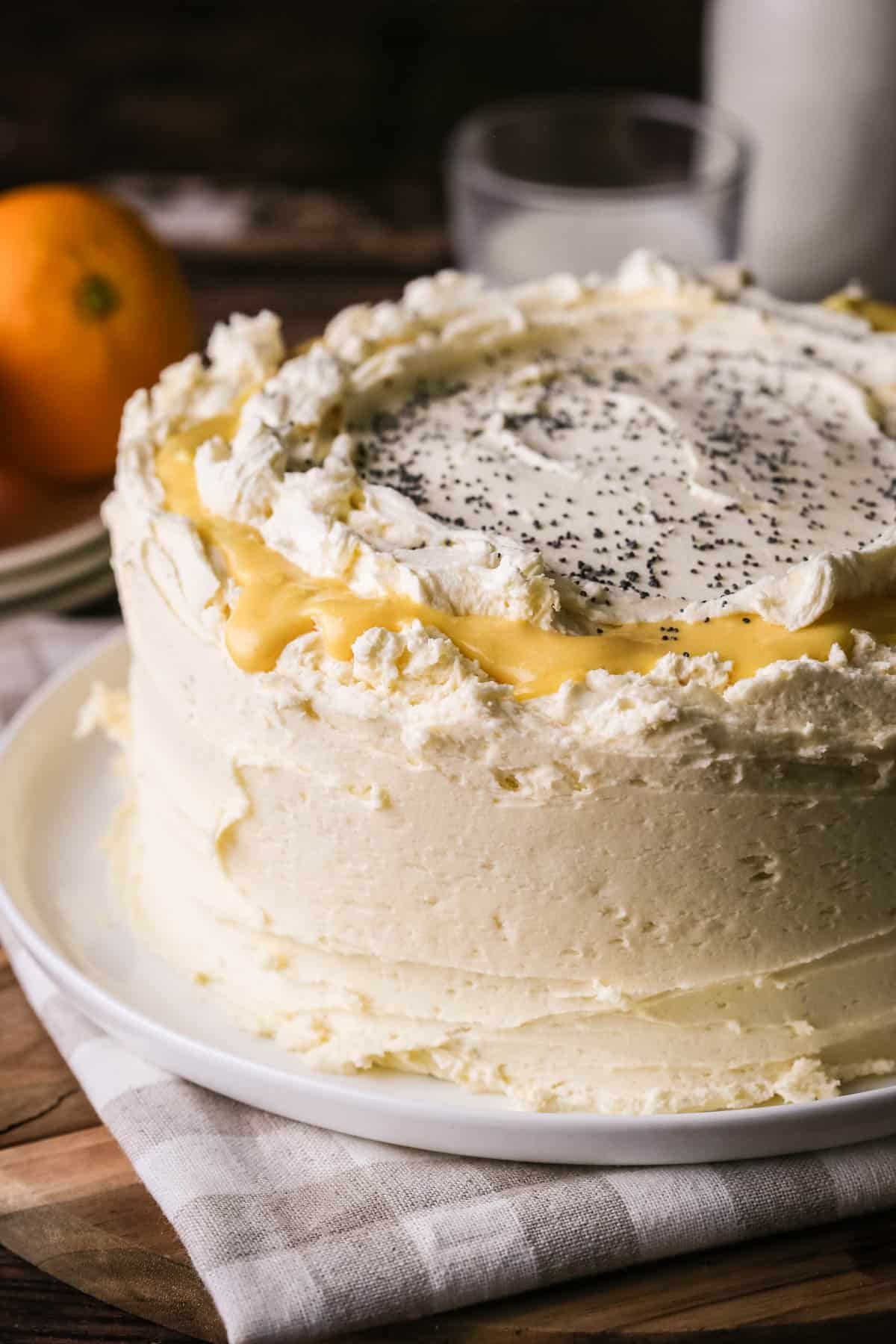 Gluten-Free Orange & Poppy Seed Cake on a plate. Thickly covered in a creamy buttercream icing with orange curd.