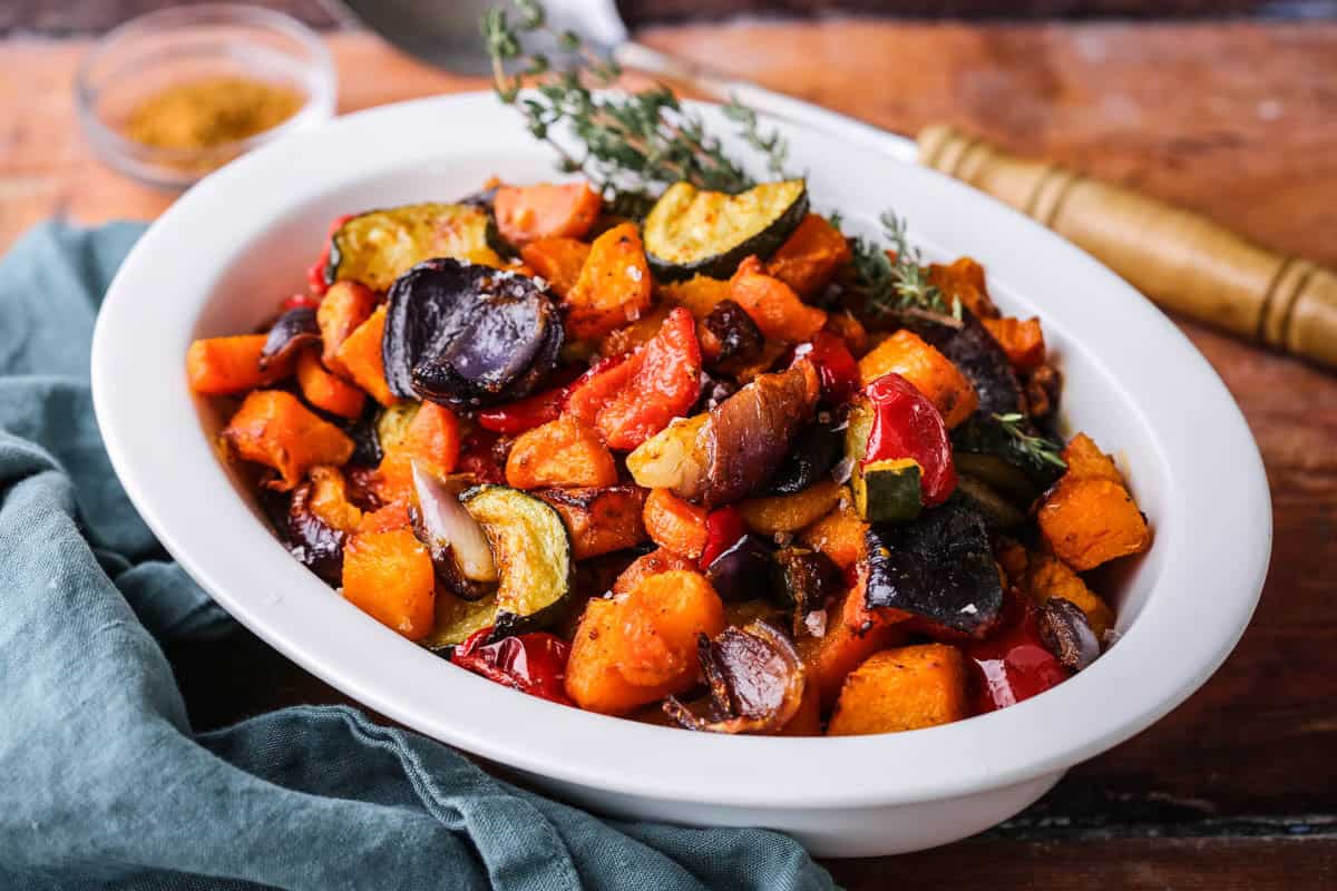 Roasted vegetables presented in a serving dish with thyme.