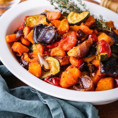 Roasted vegetables presented in a serving dish with thyme.