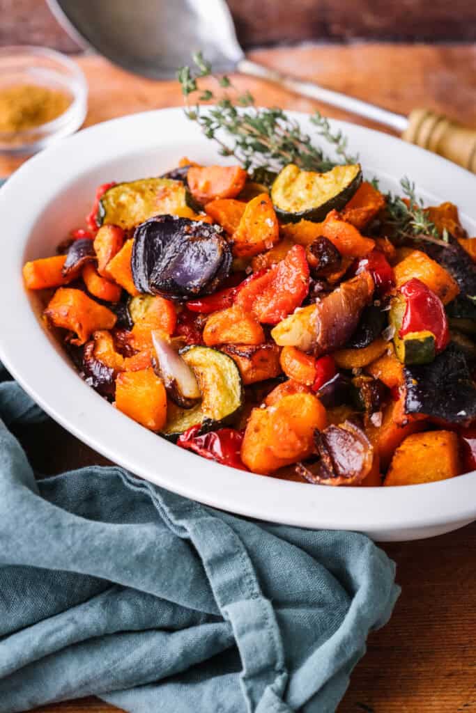 Roasted vegetables presented in a serving dish with thyme.