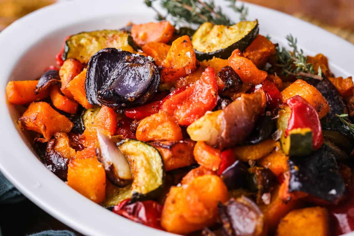 Roasted vegetables presented in a serving dish with thyme.