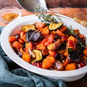 Roasted vegetables presented in a serving dish with thyme.