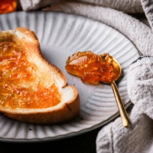 Seville Orange Marmalade on toast next to a teaspoonful of marmalade.