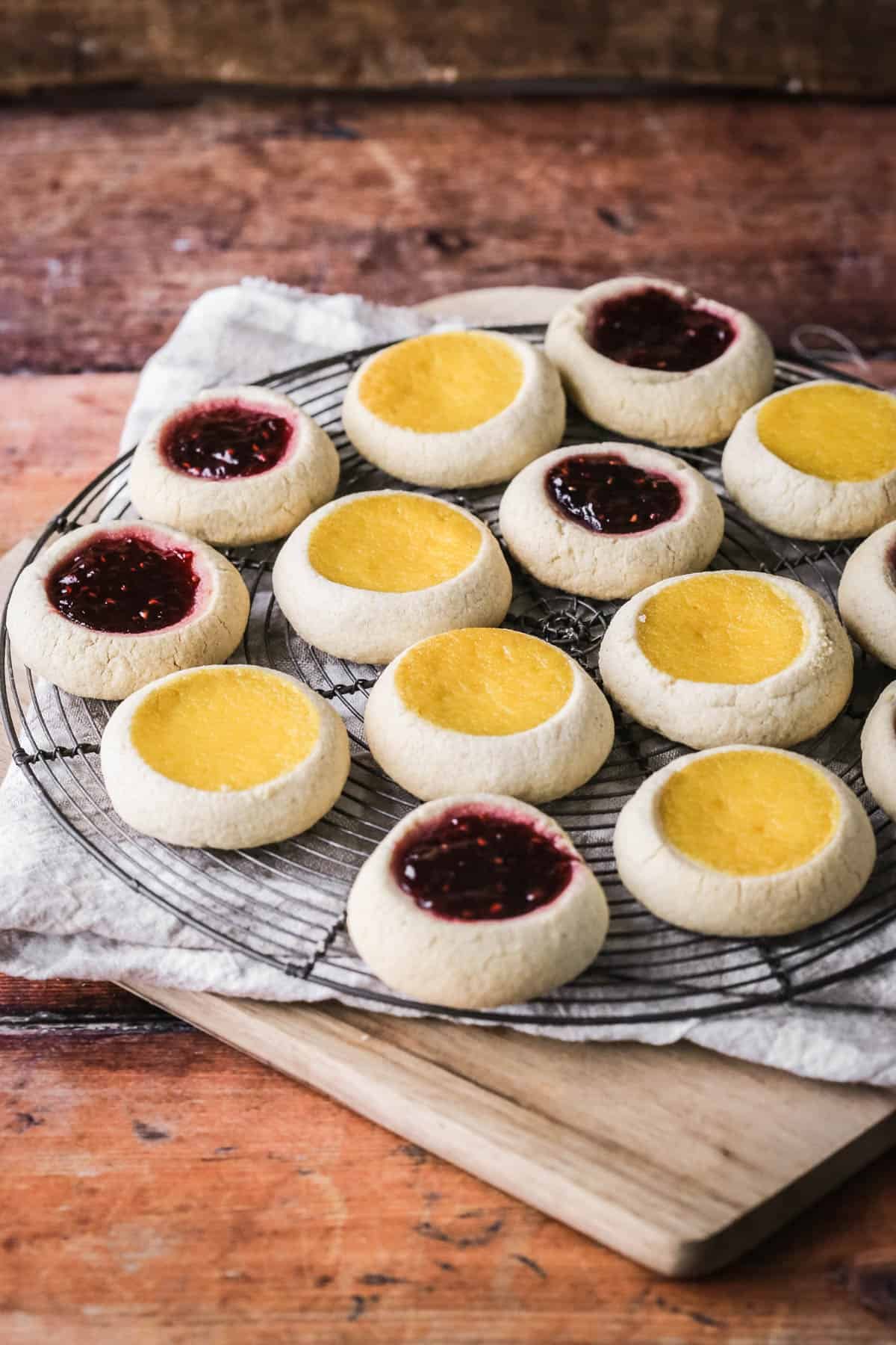 Cooling rack filled with thumbprint cookies with jam and orange curd fillings.