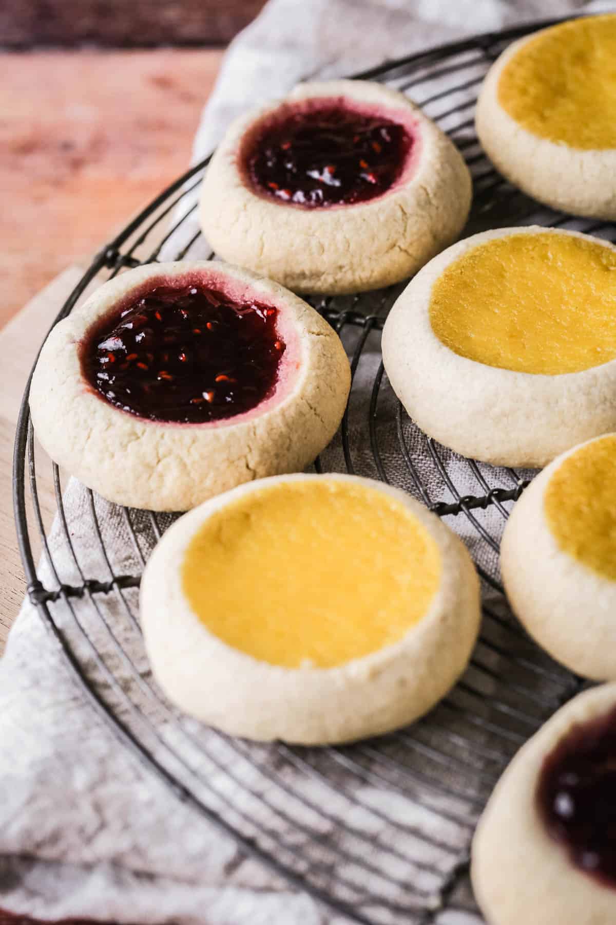 Cooling rack filled with thumbprint cookies with jam and orange curd fillings.