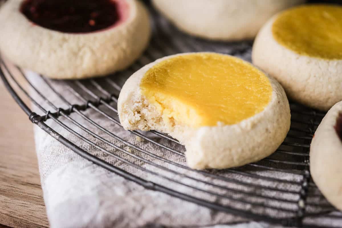 Bite taken from thumbprint cookie showing soft slightly crumbly shortbread style cookie.