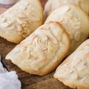 Gluten-Free Almond Tuile on a board golden crisp edges on the outside and paler in the centre, covered with flaked almonds.