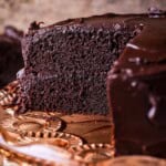 Chocolate fudge cake cut into showing soft moist sponge and richly intense creamy ganache.