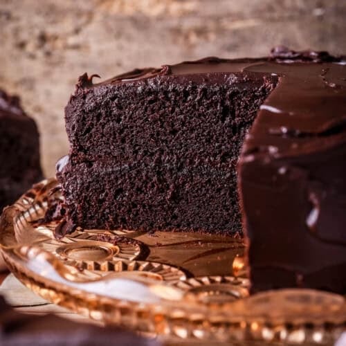 Chocolate fudge cake cut into showing soft moist sponge and richly intense creamy ganache.