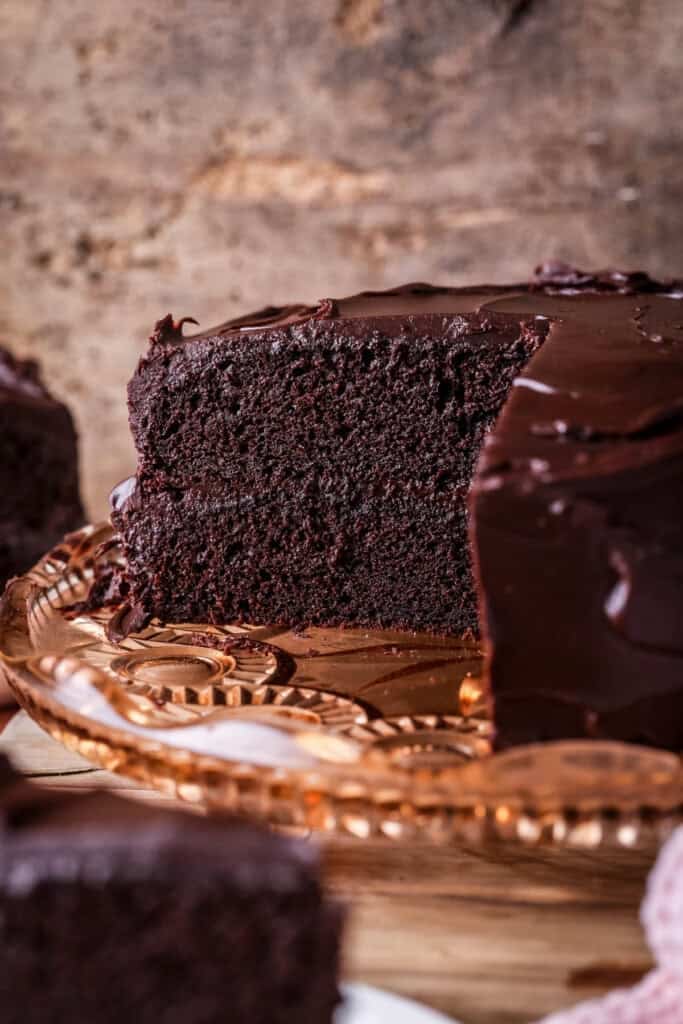 Chocolate fudge cake cut into showing soft moist sponge and richly intense creamy ganache.