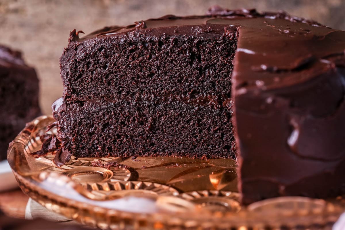 Chocolate fudge cake cut into showing soft moist sponge and richly intense creamy ganache.