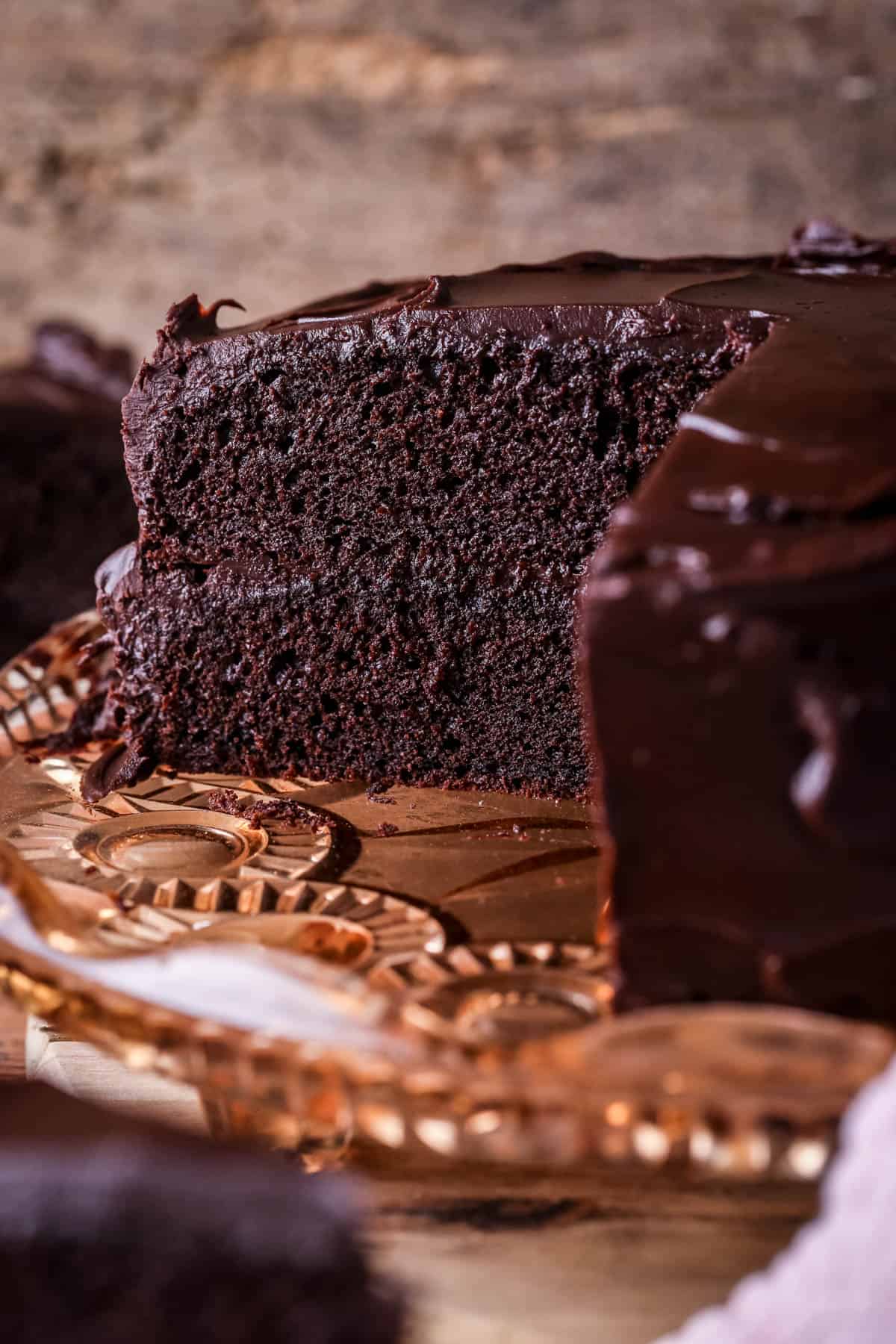 Chocolate fudge cake cut into showing soft moist sponge and richly intense creamy ganache.