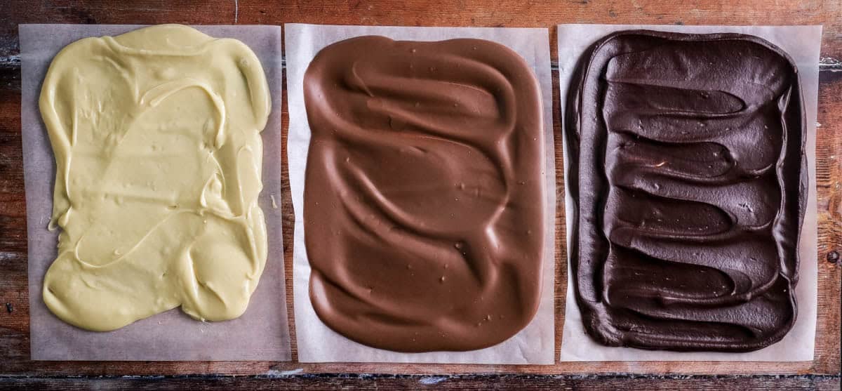 White Chocolate Ganache, milk chocolate ganache and dark chocolate ganache set on baking parchment ready for chocolate truffle rolling.