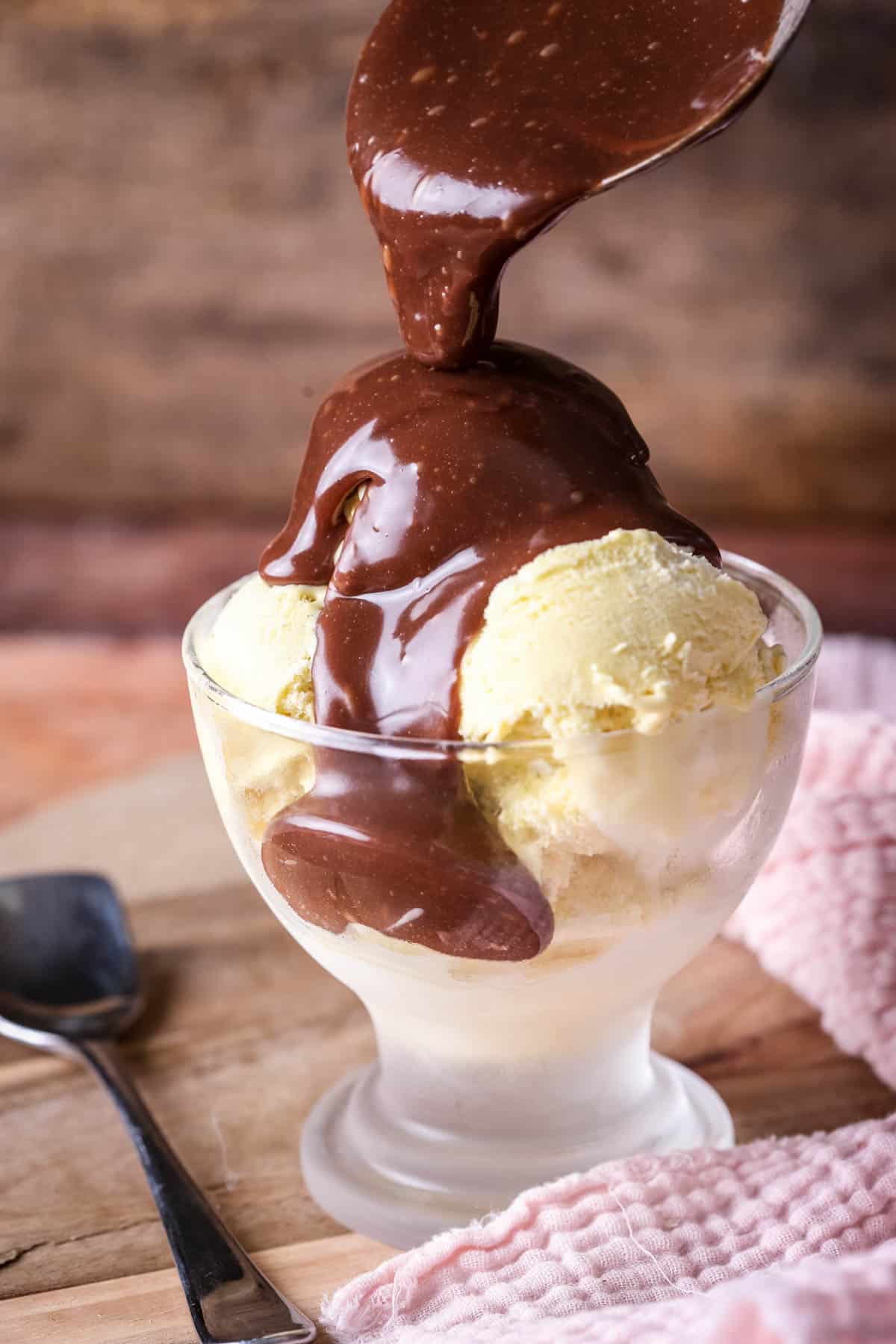 Milk Chocolate Ganache thickly poured over vanilla ice cream in a bowl.