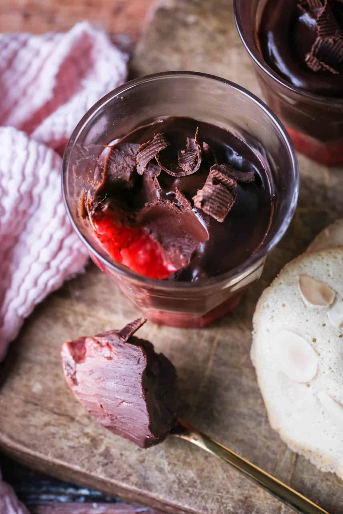 Chocolate Pots for Two with fruity raspberry bottom layer. Silky spoonful taken out showing creamy ganache inside and raspberries at the bottom.