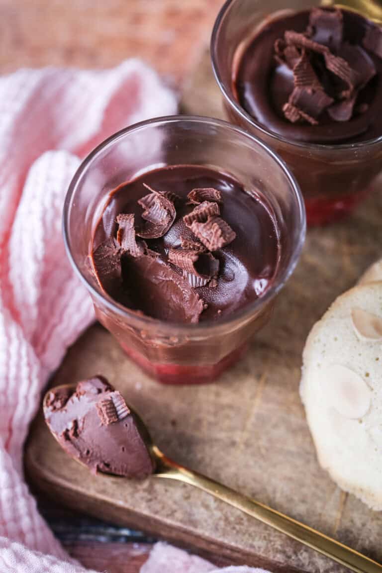 Chocolate Pots for Two with fruity raspberry bottom layer. Silky spoonful taken out showing creamy ganache inside.