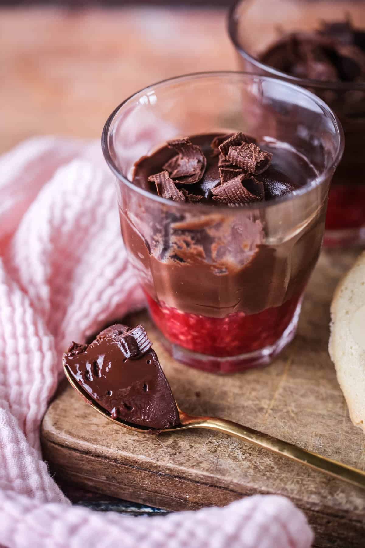 Chocolate Pots for Two with fruity raspberry bottom layer. Silky spoonful taken out showing creamy ganache inside.