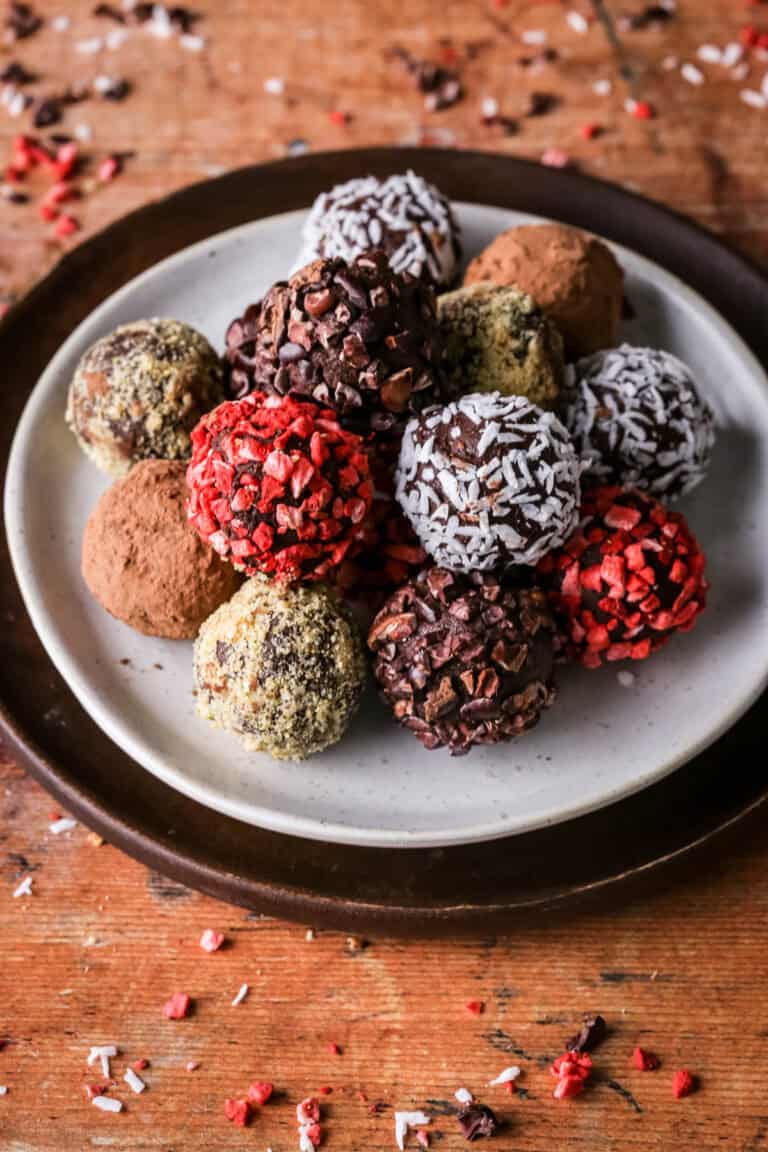 Pile of homemade chocolate truffles on a plate rolled in a variety of coatings.