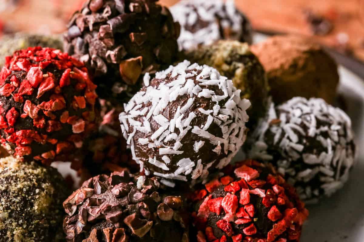 Pile of homemade chocolate truffles on a plate rolled in a variety of coatings.