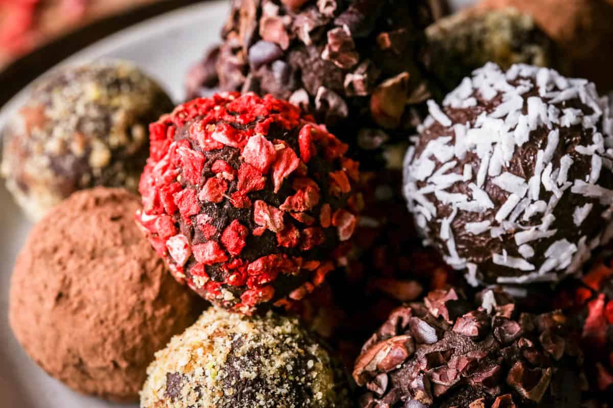 Pile of homemade chocolate truffles on a plate rolled in a variety of coatings.