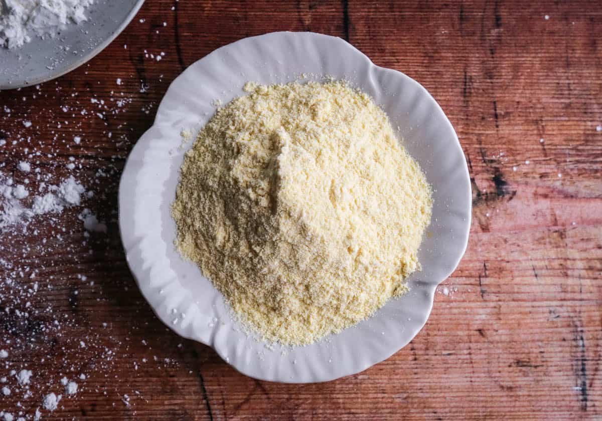 A plate of fine cornmeal on a table. It's pale yellow with a very fine grain.