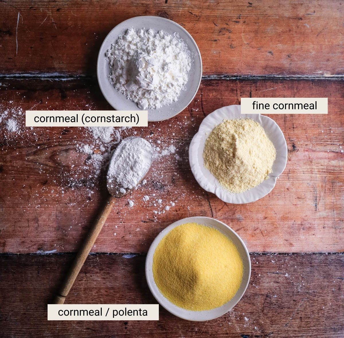 Cornflour, fine cornmeal and polenta on a table showing the differences between how they look.