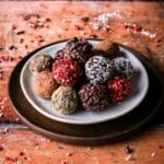 Pile of homemade chocolate truffles on a plate rolled in a variety of coatings.
