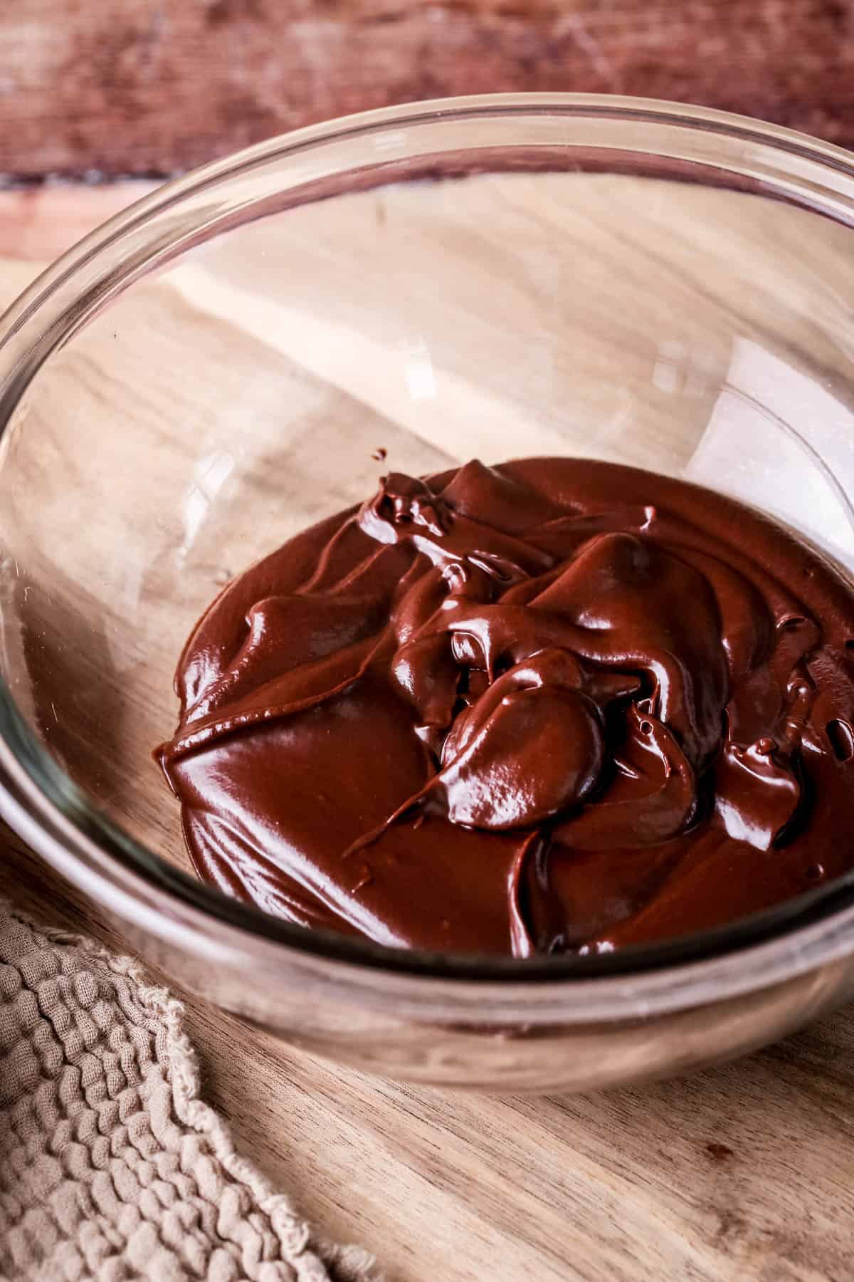 Thick smooth yet still a little runny chocolate ganache ready for setting in a bowl.