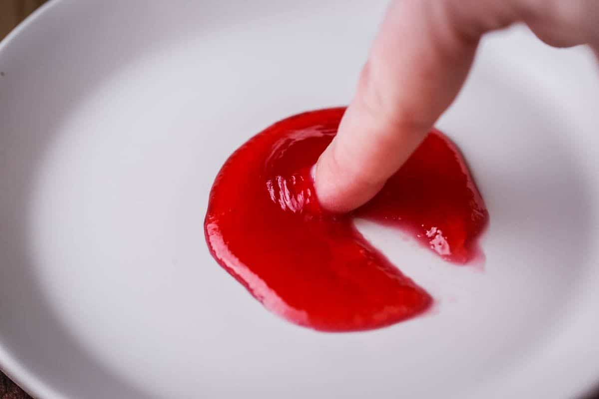 Finger is pushing through jam which is wrinkling up and the jam has a clear path but isn't too solid, in fact it is moving slowly back together. The jam is perfectly set.