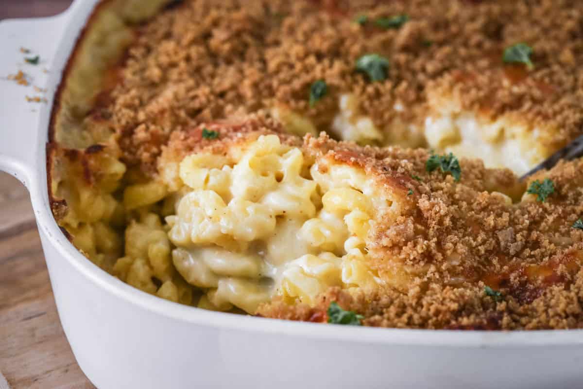 Serving spoon scooping out a portion showing ultra creamy and cheesy sauce clinging to tender macaroni pasta. With a golden crisp topping.