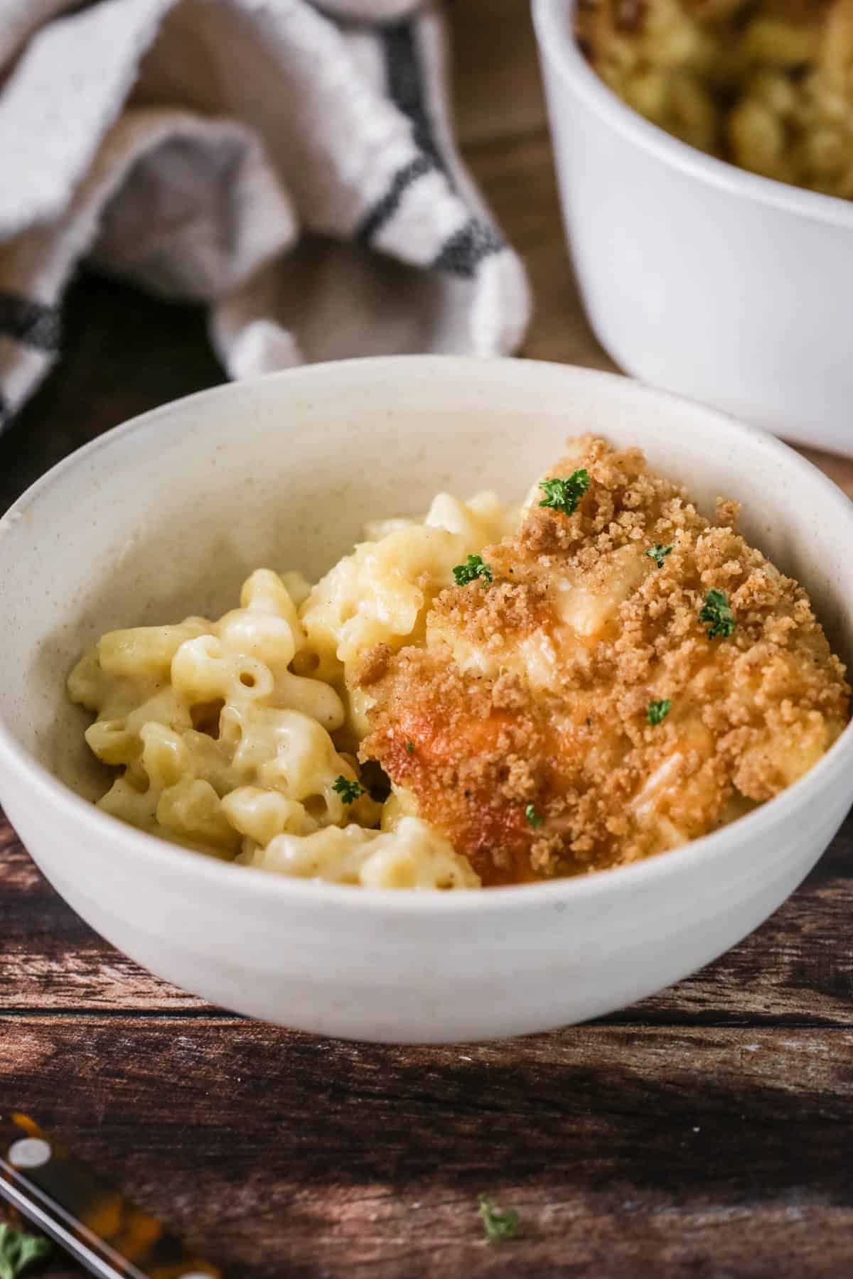 A portion of gluten-free mac and cheese in a bowl showing ultra creamy and cheesy sauce clinging to tender macaroni pasta. With a golden crisp topping.