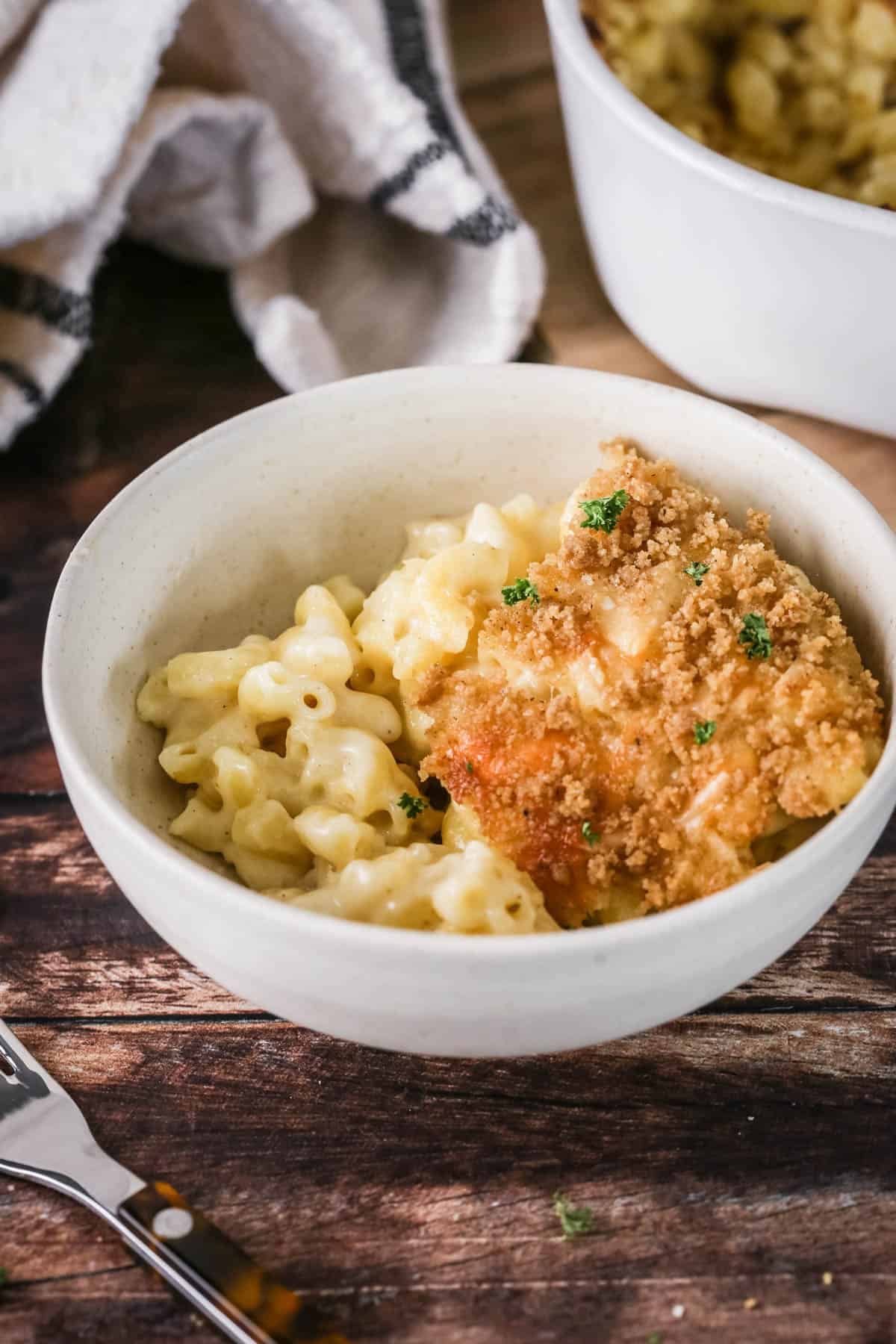 A portion of gluten-free mac and cheese in a bowl showing ultra creamy and cheesy sauce clinging to tender macaroni pasta. With a golden crisp topping.